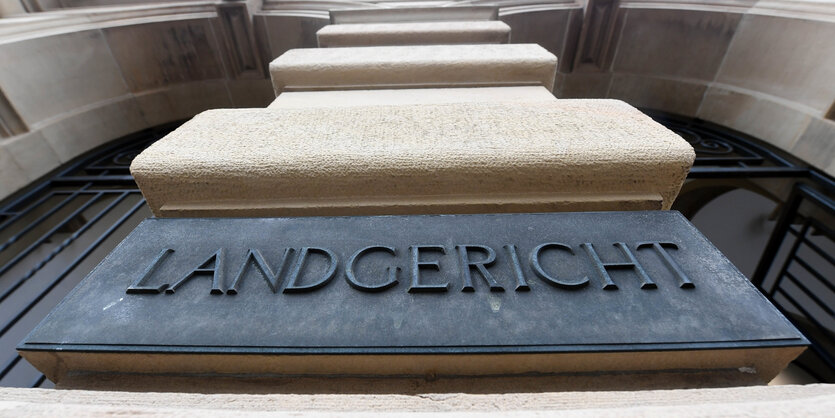 Man sieht ein Schild, auf dem Landgericht steht, von unten fotografiert.