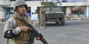 Ein mit Maschinengewehr bewaffneter Soldat steht vor einem Wahllokal