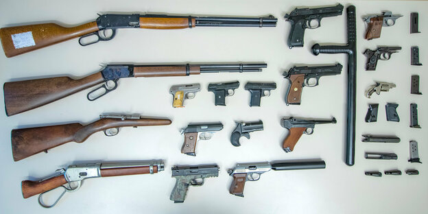 Gewehre, Pistolen, Magazine und ein Schlagstock liegen auf einem Tisch