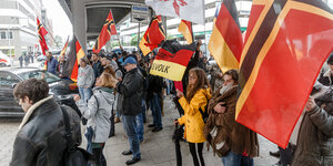 Am Hamburger Rödingsmarkt schwenkt eine Gruppe Menschen schwarz-rot-goldene Fahnen und solche der identitären Bewegung