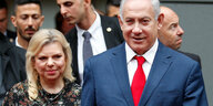 Sara und Benjamin Netanjahu. Im Hintergrund sind mehrere Männer zu sehen.