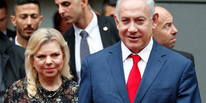 Sara und Benjamin Netanjahu. Im Hintergrund sind mehrere Männer zu sehen.