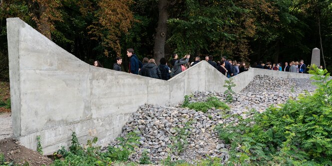 Mauer am Rand eines von Steinen belegten Massengrabs