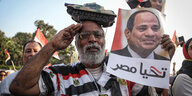 Ein Demonstrant trägt einen Panzer auf dem Kopf und ein Plakat von Abd el-Fattah el-Sisi