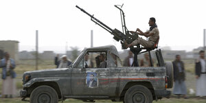 Huthi-Rebellen fahren während einer Versammlung auf einem Pick-Up mit darauf montierter Waffe