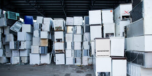 Alte Kühlschränke sind in einer Halle einer Recycling Firma übereinander gestapelt