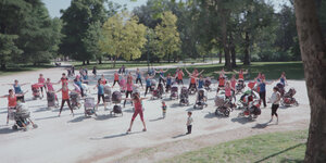 Dutzende Frauen mit Kinderwagen machen Sport in einem Park