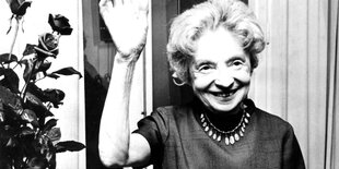 Eine freundliche ältere Dame, es ist Nelly Sachs, winkt