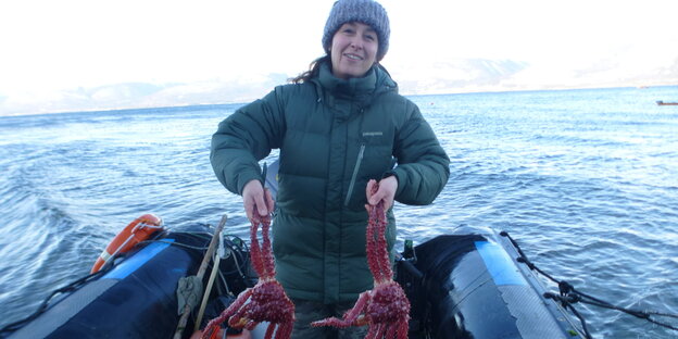 Krabbenfischerin Diana Méndez präsentiert zwei Krabben auf ihrem Boot.
