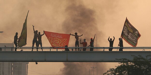 Demonstranten mit Flaggen auf einer Brücke, dunkle Rauchschwaden