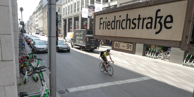 Straßenschild der Freidrichstraße, dahinter Straße mit Autos und Fahrradfahrer