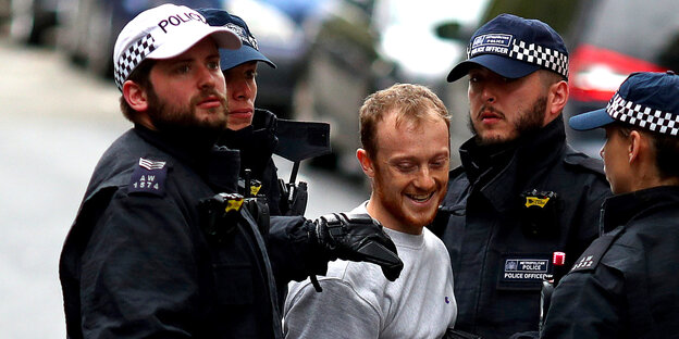 ein Mann - umgeben von mehreren uniformierten Polizeibeamten