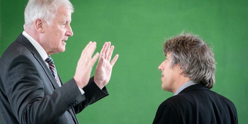 Bundesinnenminister Horst Seehofer unterhält sich mit Pro-Asyl-Geschäftsführer Günther Burkhardt. Seine Hände sind erhoben, die Handflächen weisen zu Burkhardt.