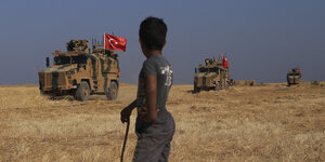 Ein syrischer Junge schaut auf türkische Militärfahrzeuge
