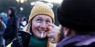 Einer jungen Frau werden weiße Punkte ins Gesicht gezeichnet