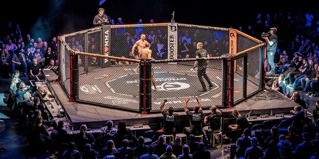 Kämpfer stehen in einem MMA-Ring in einer Hamburger Halle.