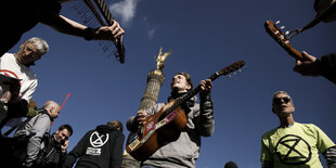 AktivistInnen von Extinction Rebellion mit Gitarren am Großen Stern um die Siegessäule. Die Bewegung hat zum Auftakt der Aktionswoche "Berlin blockieren" den Großen Stern besetzt. Die Polizei hat den Bereich weiträumig abgesperrt.