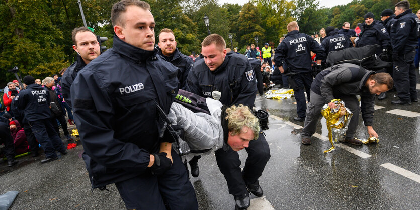 Polizisten tragen einen Aktivisten der Klimabewegung "Extinction Rebellion" während der Aktionswoche "Berlin blockieren" von einer Sitzblockade am Großen Stern an der Siegessäule