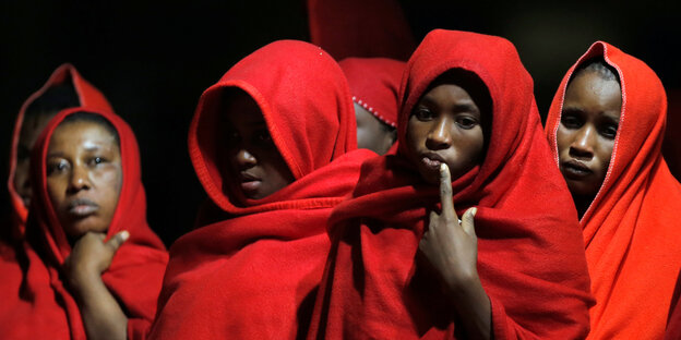Frauen mit roten Decken umhüllt wärmen sich nach der Rettung