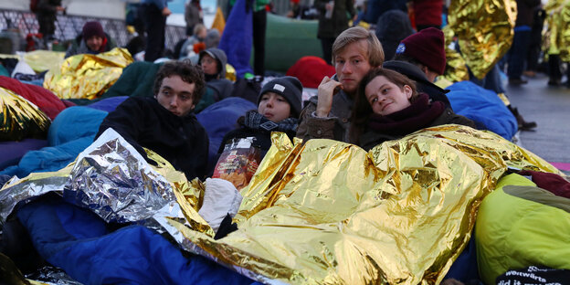 In goldene Wärmedecken gehüllt, liegen die Demonstranten auf der Marschallbrücke