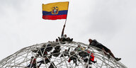 Demonstranten hießen die Flagge Ecuadors auf einer Skulptur