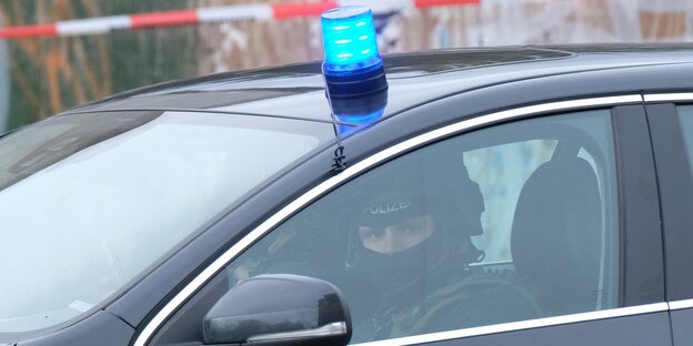 Ein Polizist im Polizeiwagen mit Blaulicht