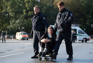 Ein Demonstrant lässt sich von Polizisten auf einem Skateboard wegschieben Ein Demonstrant lässt sich von Polizisten auf einem Skateboard wegschieben