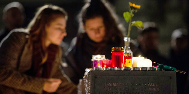 Kerzen und Totenlicht , Im Hintergrund zwei Frauen unscharf