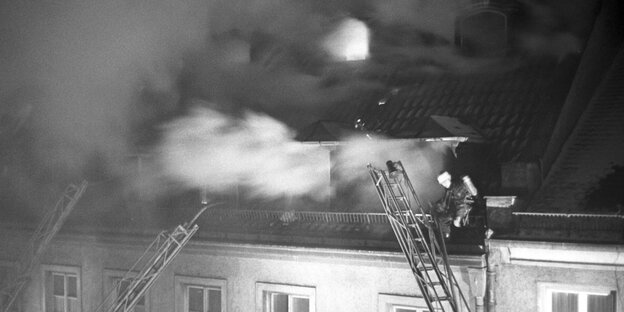 Brennender Dachstuhl und Feuerwehrmann auf einer Leiter