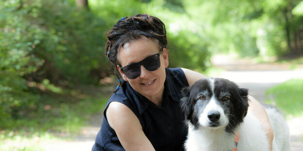 Frau mit Sonnenbrille posiert mit ihrem Hund