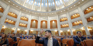 Mann im Kuppelsaal des rumänischen Parlaments hält den Daumen hoch