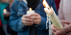 Mit Kerzen in der Hand stehen Bürger vor der Synagoge.