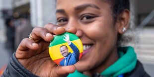 Junge Frau zeigt einen Sticker, der Premierminister Ahmed winkt