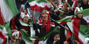 Weibliche Fans jubeln mit Iran-Flaggen im Stadion