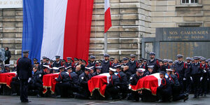 Soldaten tragen Särge. Im Hintergrund die französische Fahne