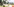 Ein Polizeiauto steht hinter eibnem Baum, davor Absperrband und Wiese
