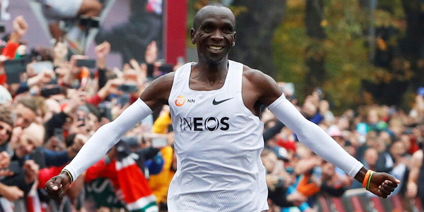 Eliud Kipchoge breitet die Arme aus, während er jubelnd ins Ziel läuft