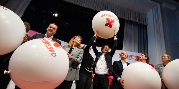 Die Kandidaten für den Parteivorsitz der SPD stehen bei der letzten Regionalkonferenz auf der Bühne und halten übergroße Ballons mit der Aufschrift "#UnsereSPD"