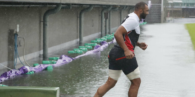 ein Rugbyspieler auf einem komplett überfluteten Spielfeld