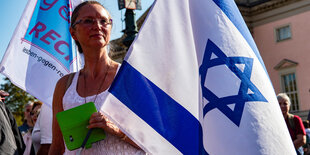 Eine Demonstrantin mit einer israelischen Flagge wartet auf den Beginn einer Demonstrationgegen Antisemitismus auf der Straße des 17. Juni.