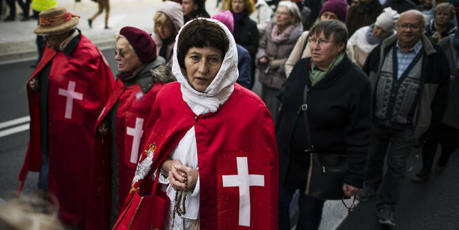 Eine Frau mit Gewand und Perlenkette in der Hand in einer Menge