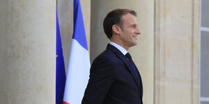 Macron mit stolzer Brust vor französischer Flagge