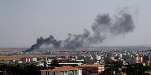 Stadt in Syrien, im Hintergrund Rauchschwaden nach Luftangriff