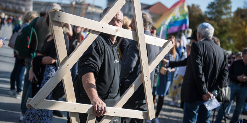 Ein Mensch traegt einen Davidstern aus Holz