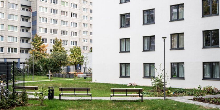 Eines der Häuser von House of Nations. Eine weisse Fassade mit vielen Fenster, davor ein Rasen und zwei Sitzbänke.