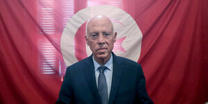Der neue tunesische Präsident steht vor einer roten Fahne.