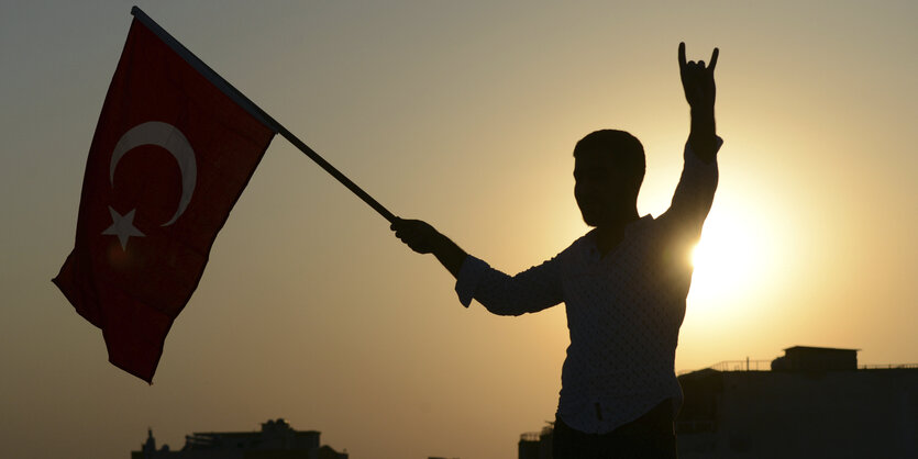 Man sieht das Profil eines Mannes, der die türkische Nationalflagge schwenkt.