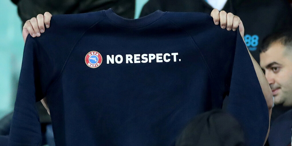 Ein Mensch hält einen Pullover hoch, auf dem "no respect" steht.