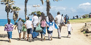 Eine Familie mit Kindern läuft an einem Stand entlang