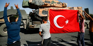 Menschen vor einem Panzer halten eine türkische Fahne hoch